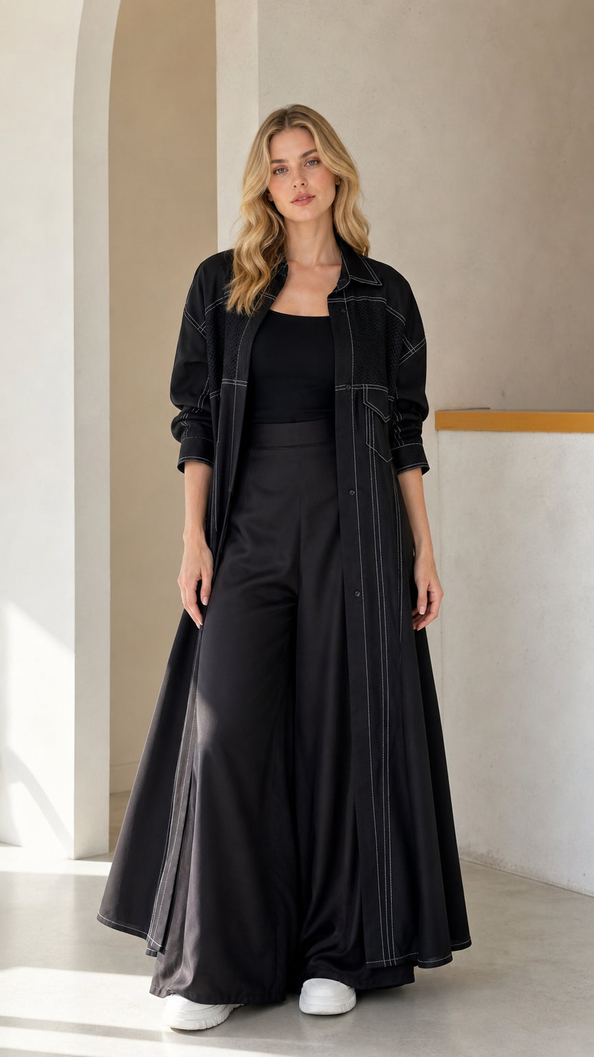 Front full view of woman wearing Black contrast stitch maxi duster coat and wide-leg trousers