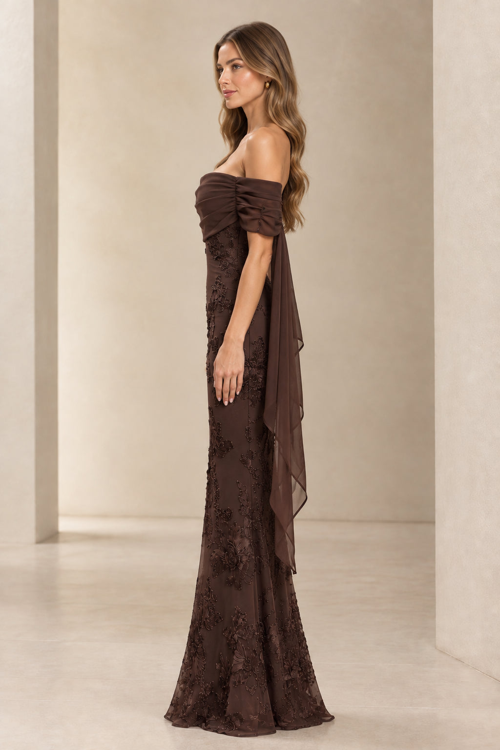 Side profile view of chocolate brown lace embroidered gown showing draped side chiffon cape detail
