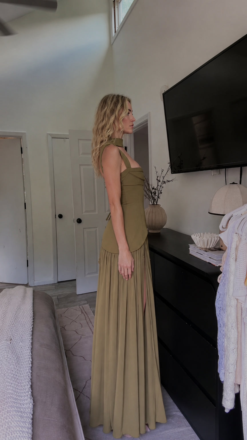 Side profile of model in olive green asymmetrical evening maxi dress