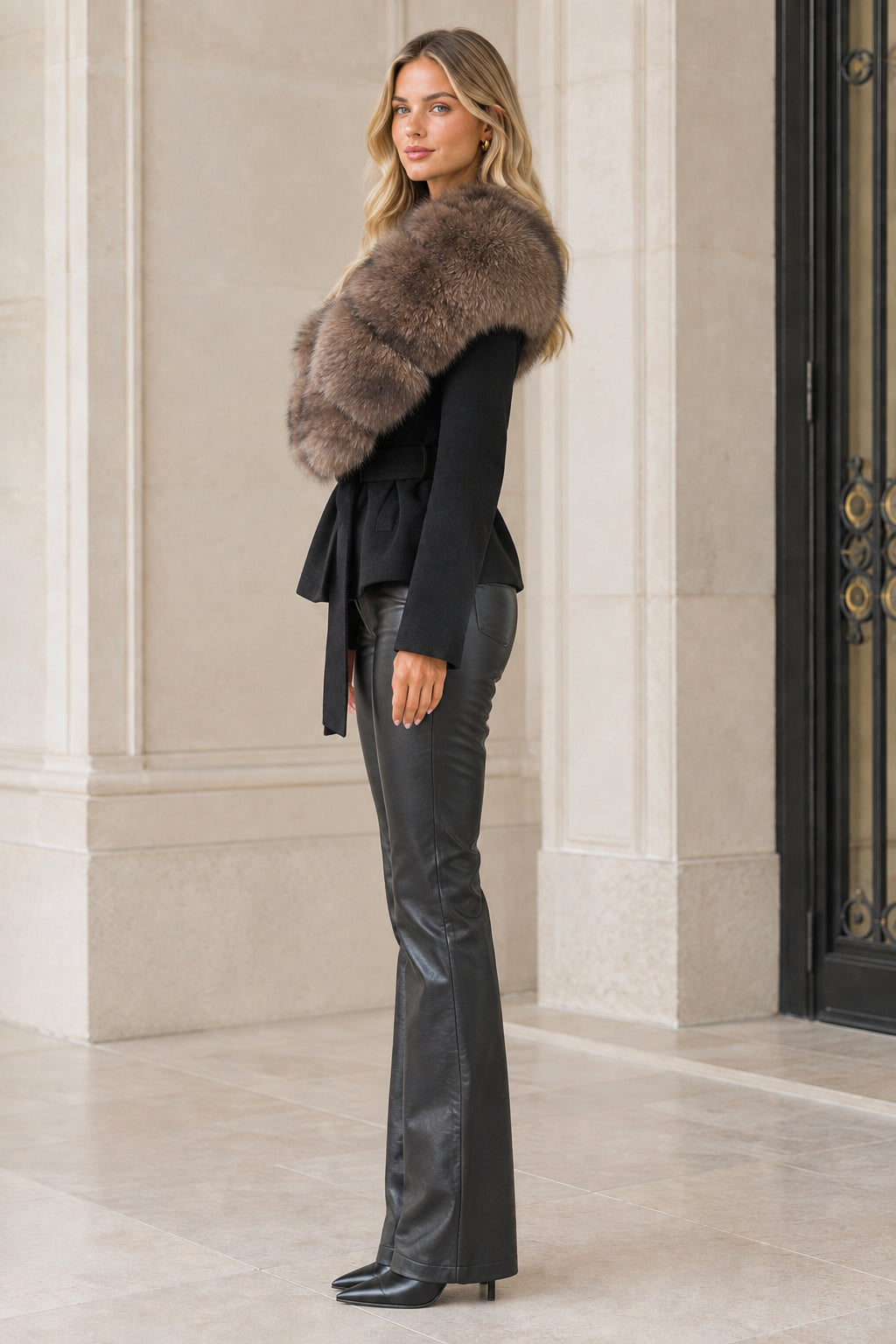 Side profile view of model wearing black belted faux fur collar jacket