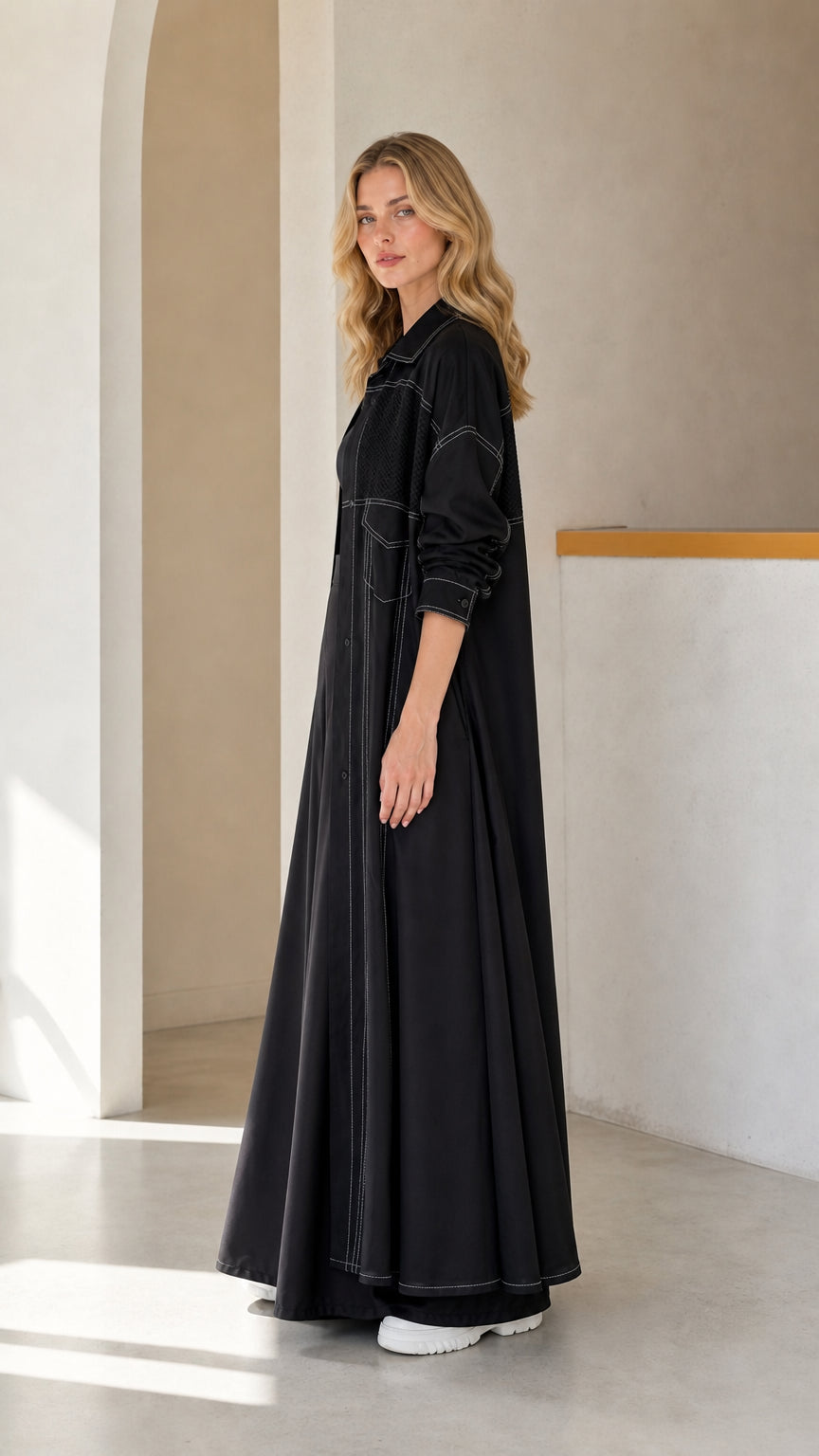 Side profile of woman wearing Black longline duster shirt coat with white topstitching