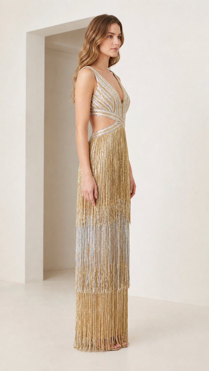 Side profile view of gold tiered fringe cutout evening gown