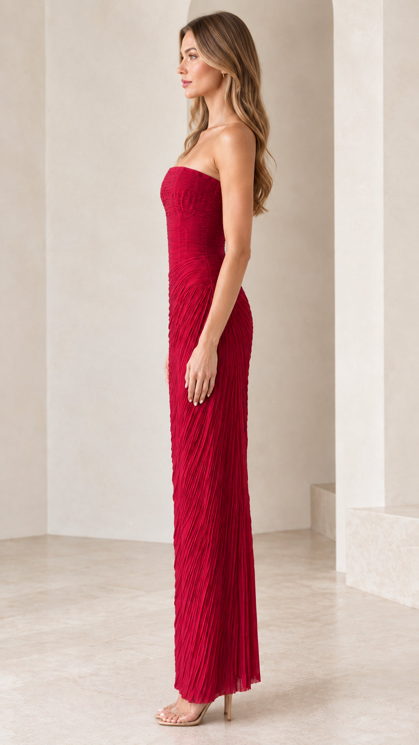 Side profile of model in strapless red pleated column evening gown