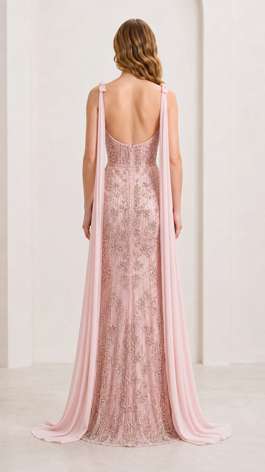 Back view of model in Blush Pink beaded floor-length dress showing low back and streamers
