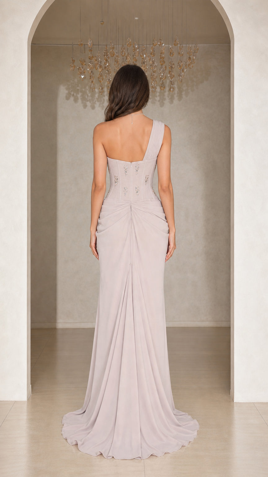 Back view of woman wearing silver grey one-shoulder maxi gown with sweep train
