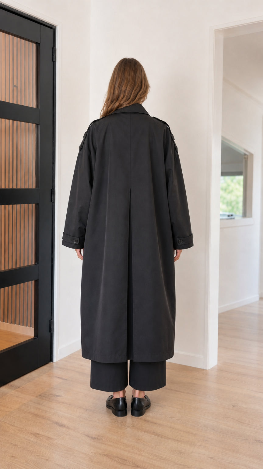 Back view of black maxi trench coat showing inverted pleat detail