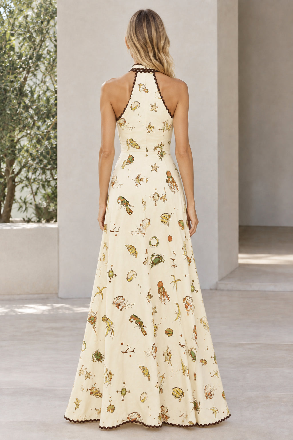 Back view of model in cream halter neck maxi dress showing open upper back