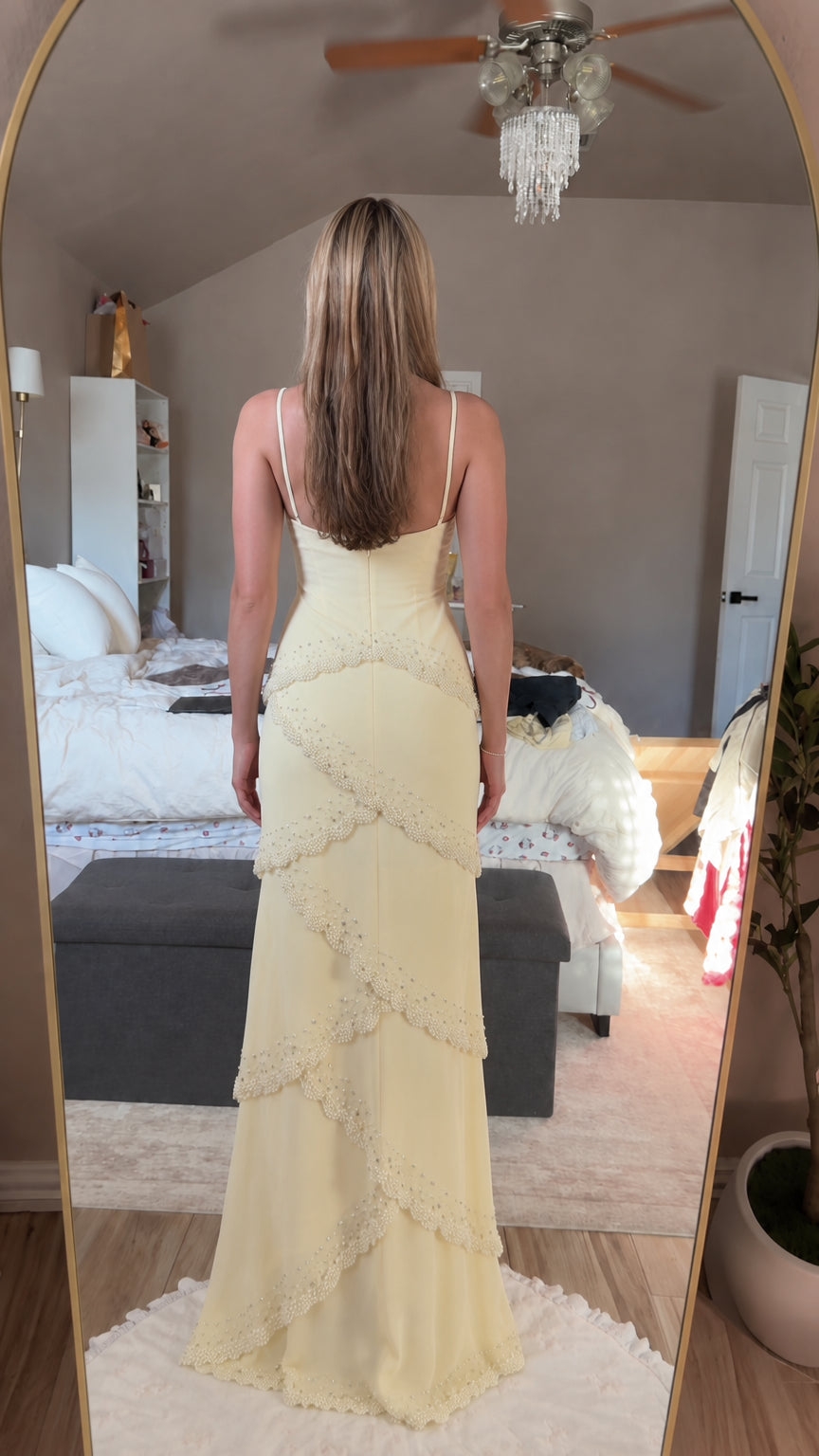 Back view of pastel yellow spaghetti strap tiered maxi dress on model