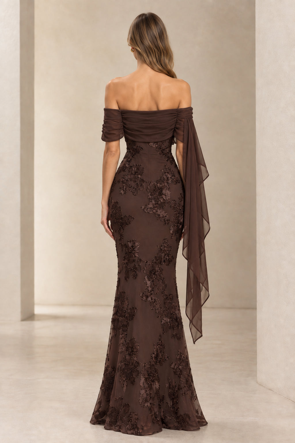 Back view of model in chocolate brown off-the-shoulder evening gown with floral embroidery
