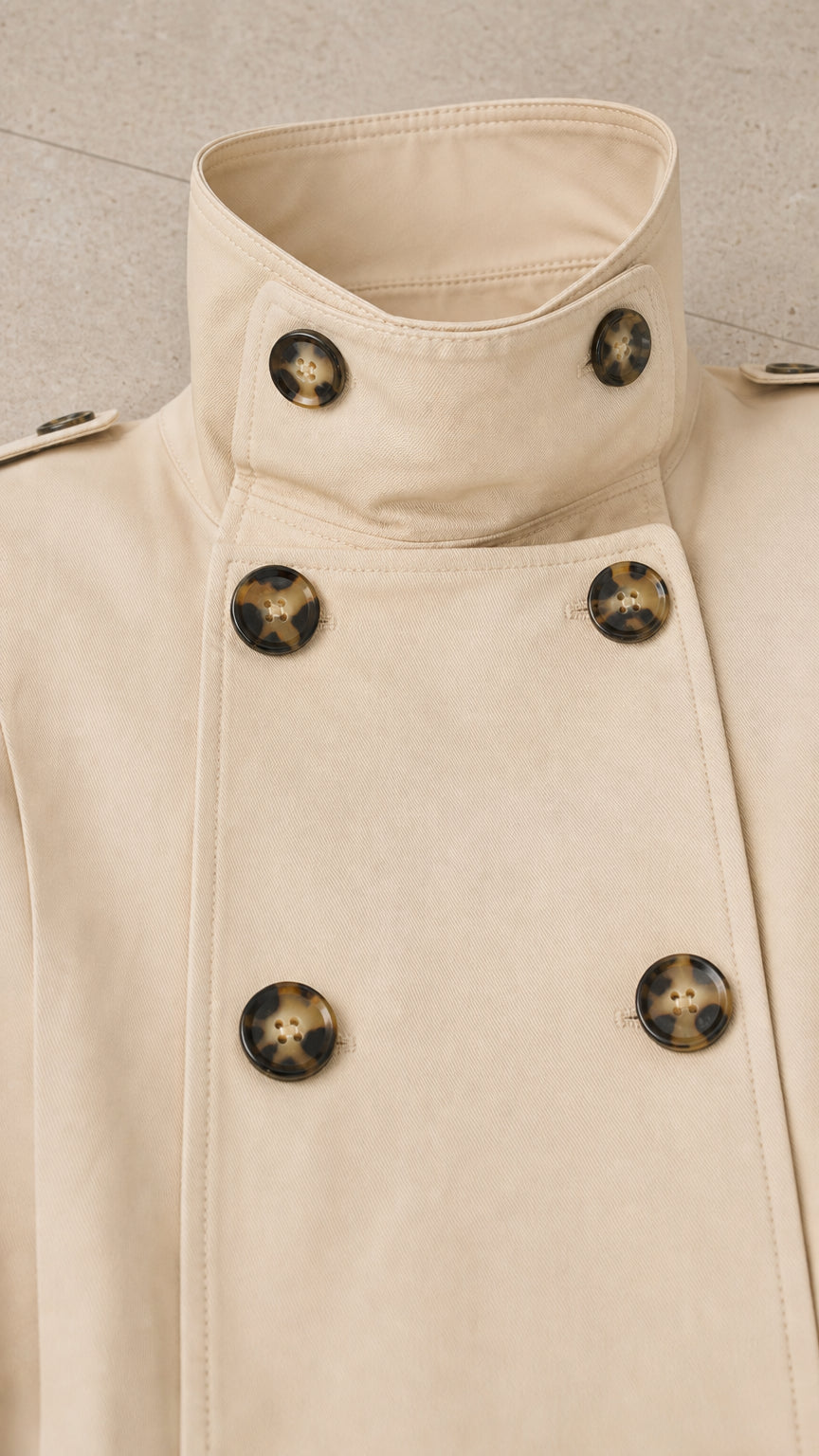 Close-up detail of cream trench jacket stand collar and tortoiseshell buttons