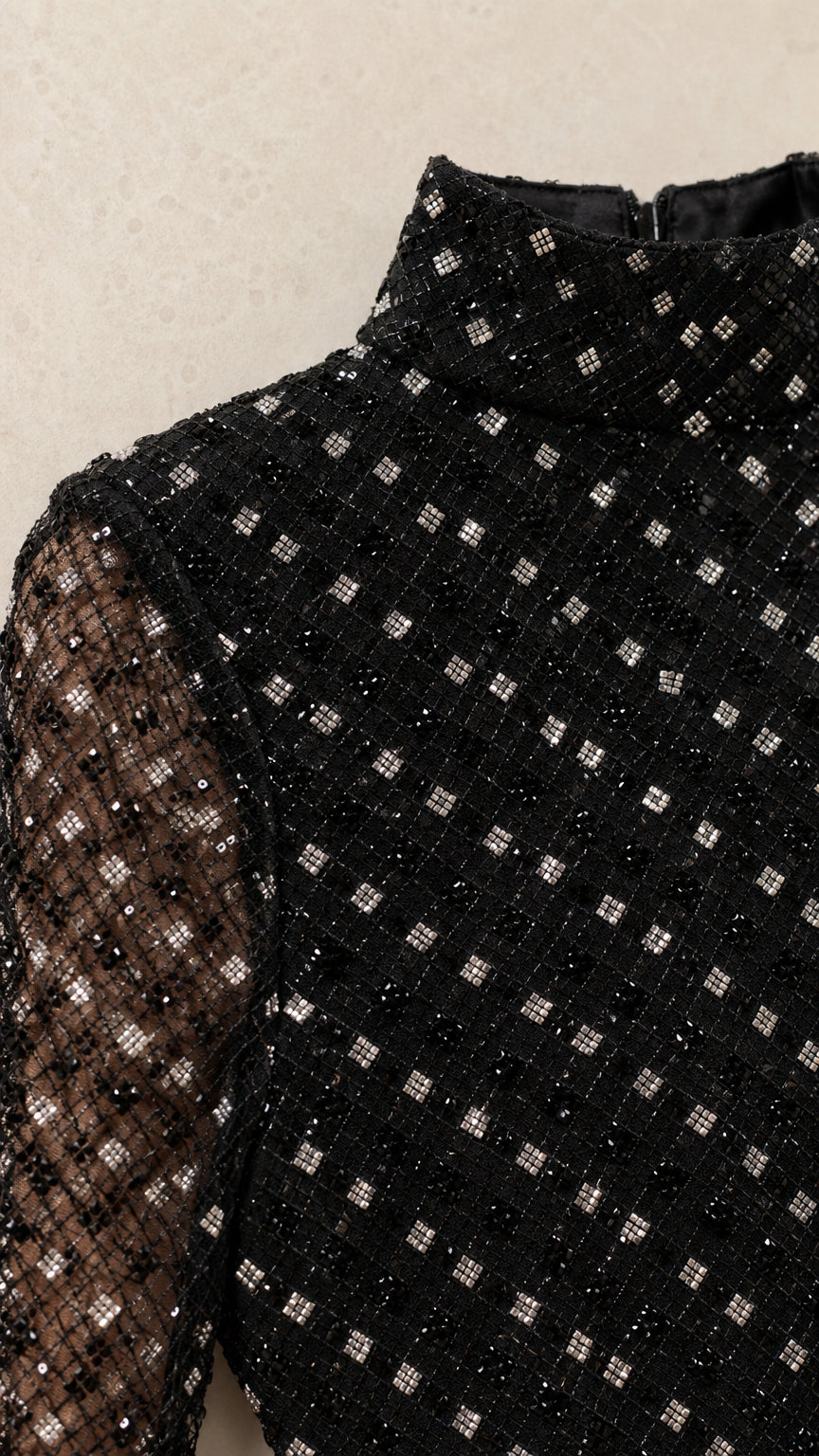 Close-up detail of black high mock neck and geometric sequin embellishment on mesh fabric