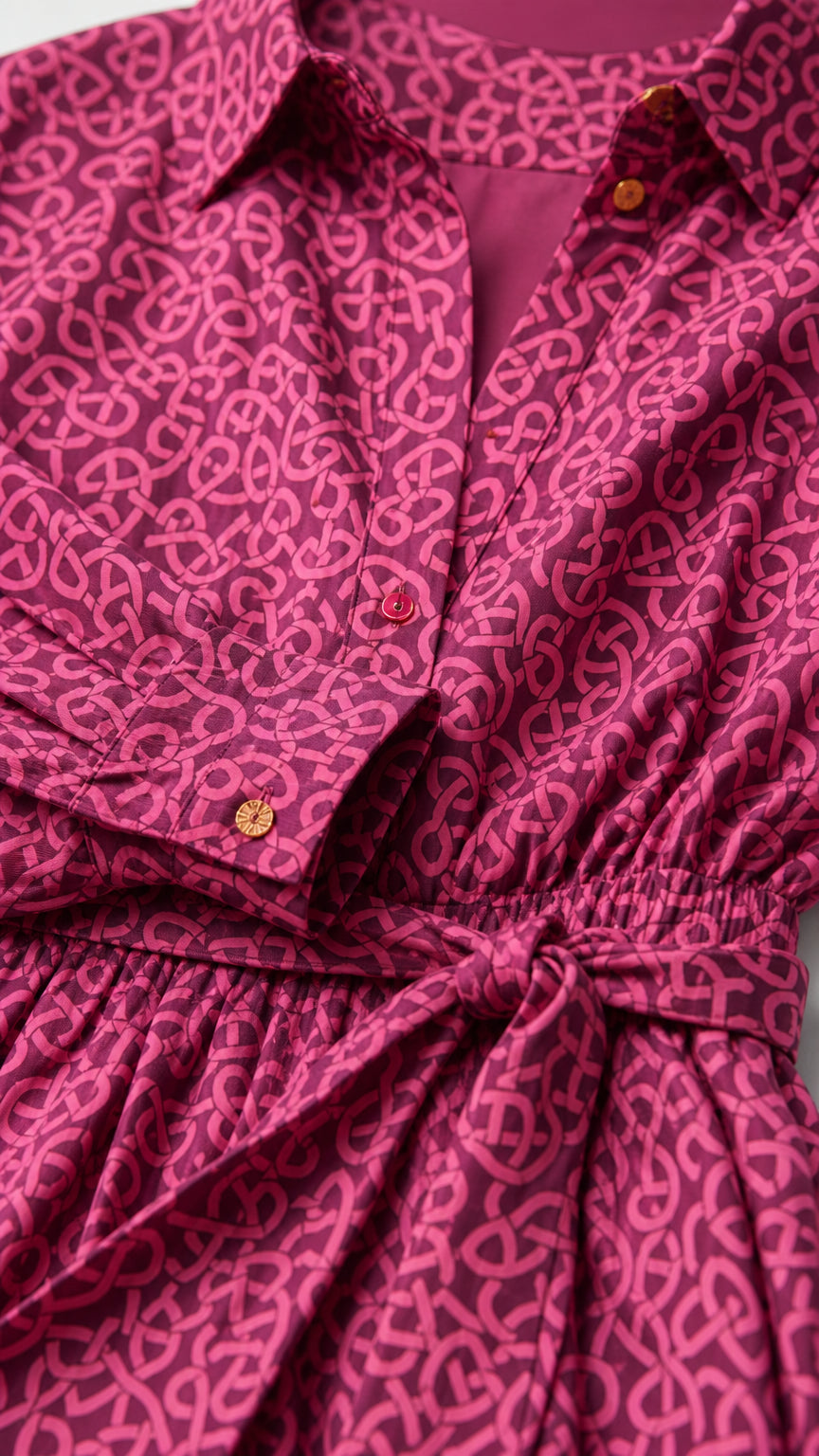 Close-up detail of collar, button placket, cuffs, and waist tie on magenta printed shirt dress