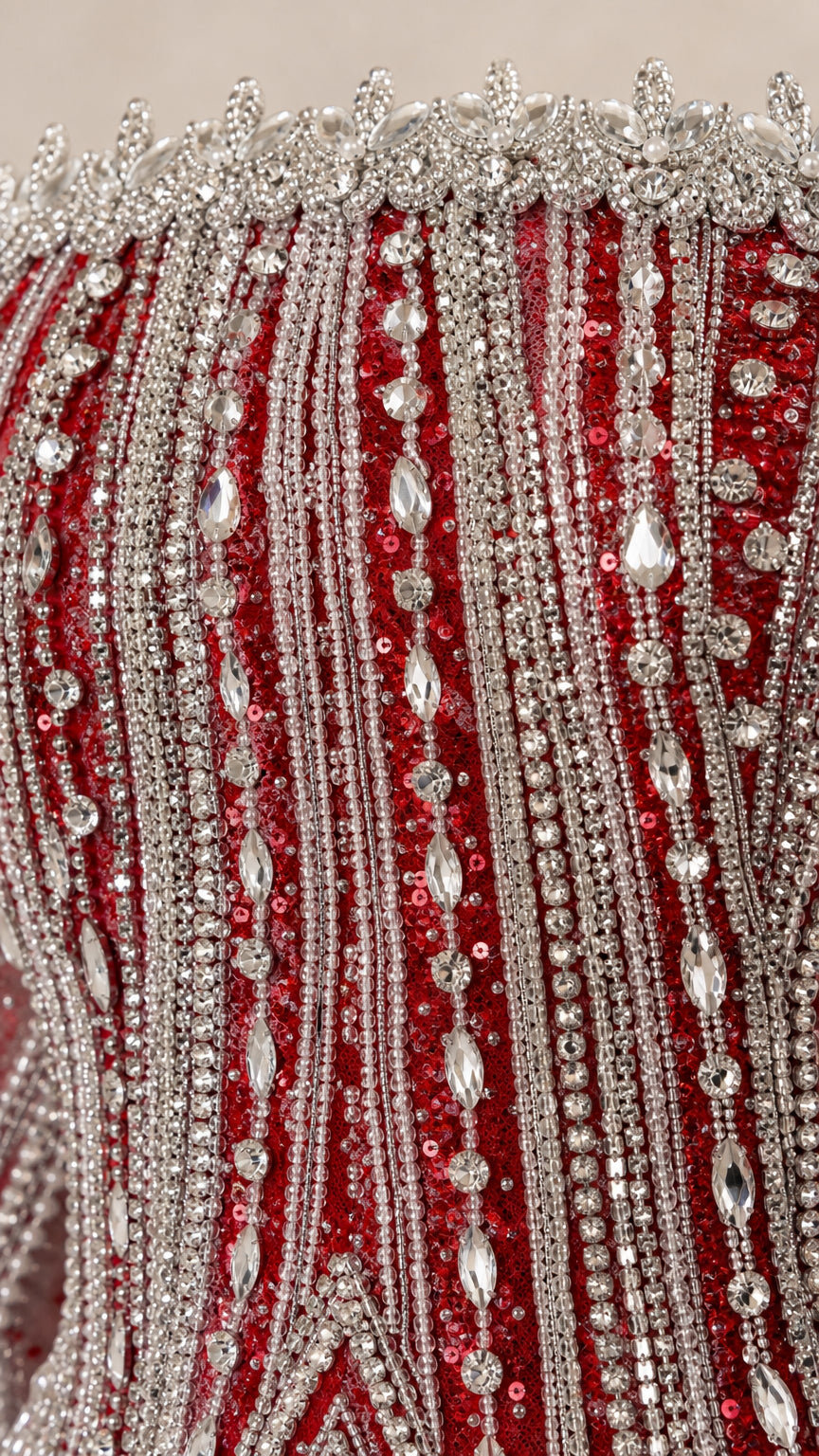 Close-up detail of crystal beadwork and sequin embellishments on red fabric