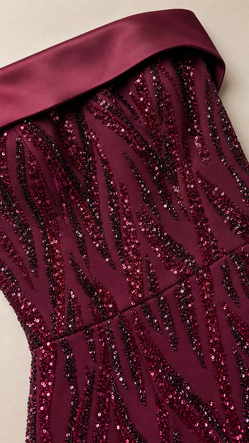 Close-up detail of burgundy folded satin band neckline and intricate sparkling sequin pattern