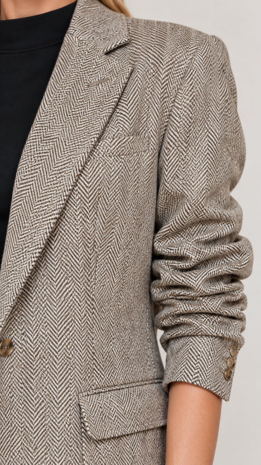 Close-up detail of herringbone textured fabric, notched lapel, and flap pocket