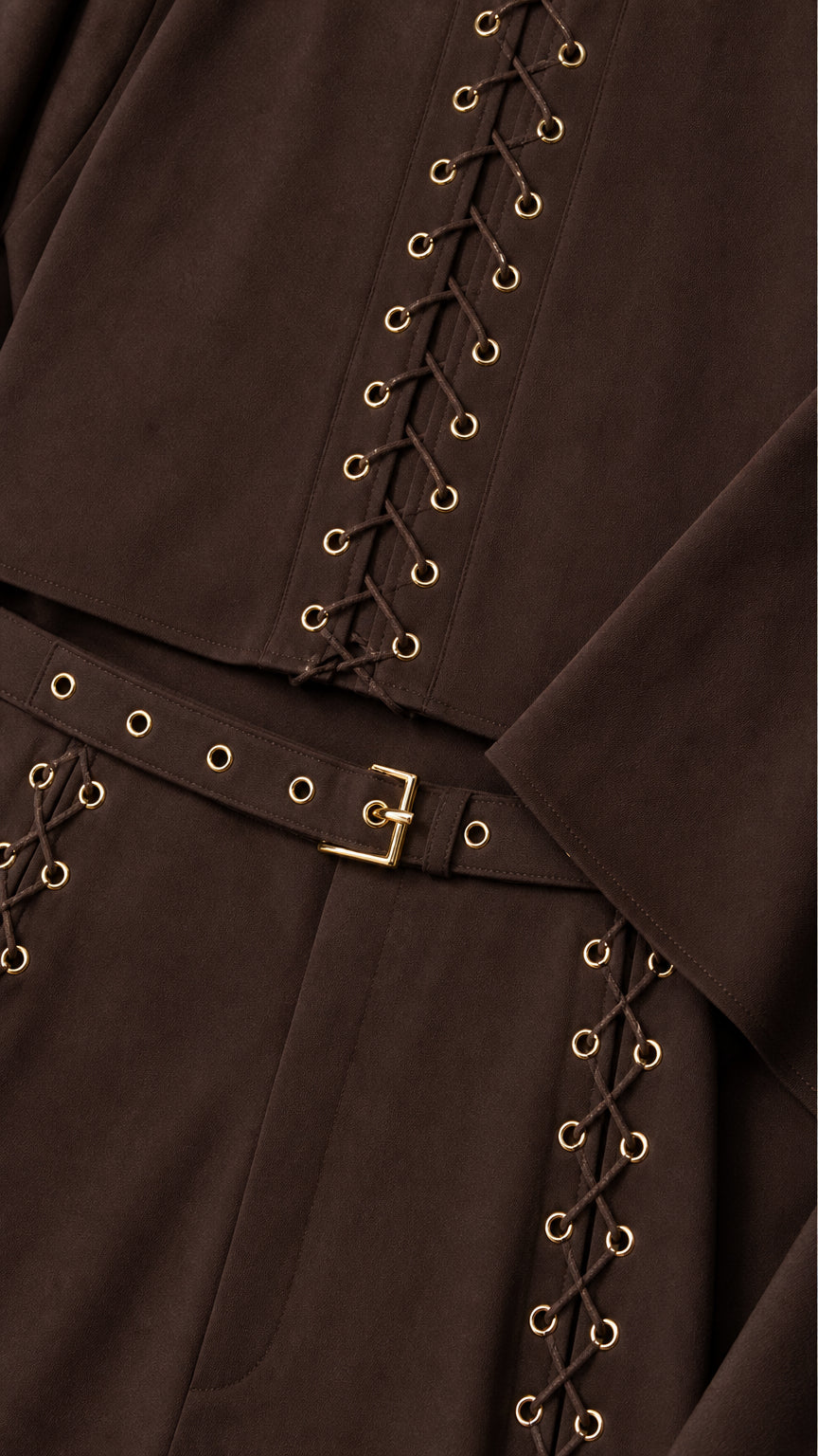 Close-up detail of metal eyelet grommets, lace-up cord accents, and belted waistband