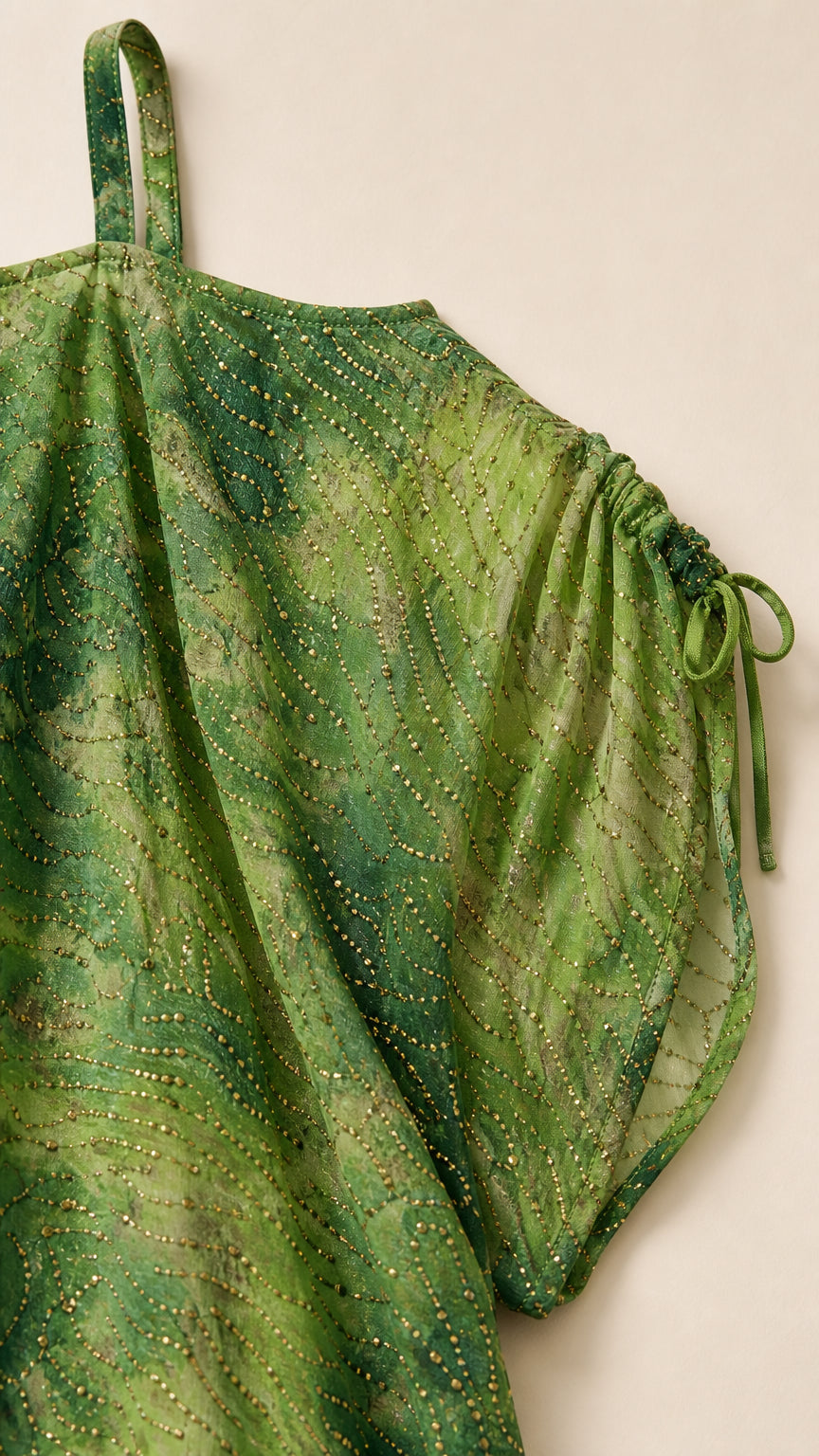 Close-up detail of green fabric with delicate embellishments and drawstring sleeve tie