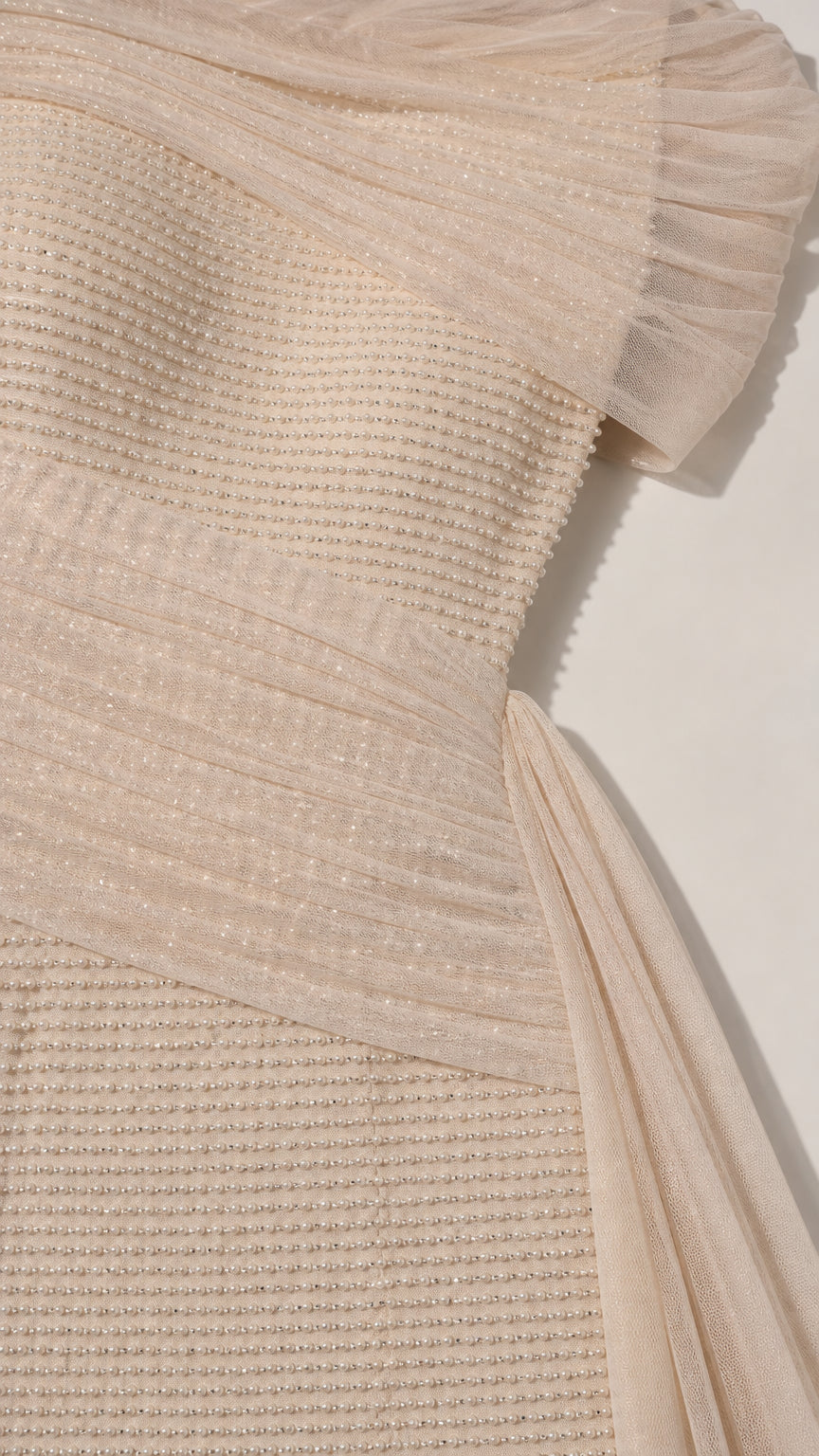 Close-up detail of textured fabric and ruched shoulder drape on evening gown