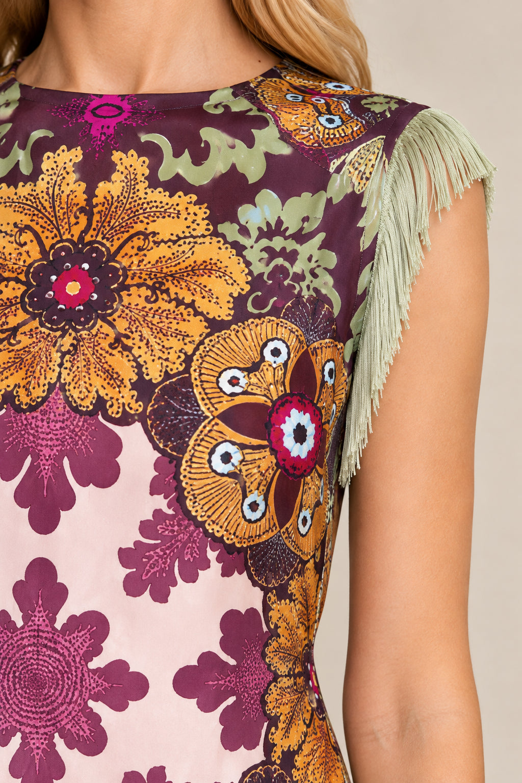 Close-up detail of jewel neckline, floral tapestry print, and shoulder fringe on Plum dress