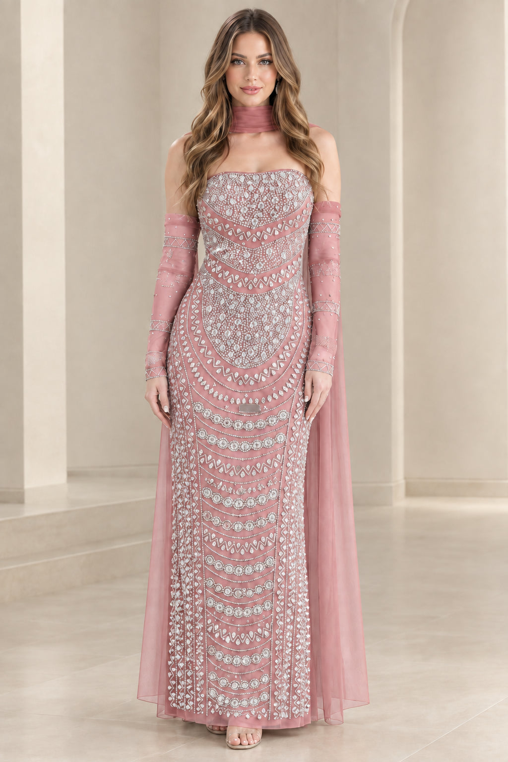Model wearing dusty pink embellished formal column gown with sheer cape sleeves