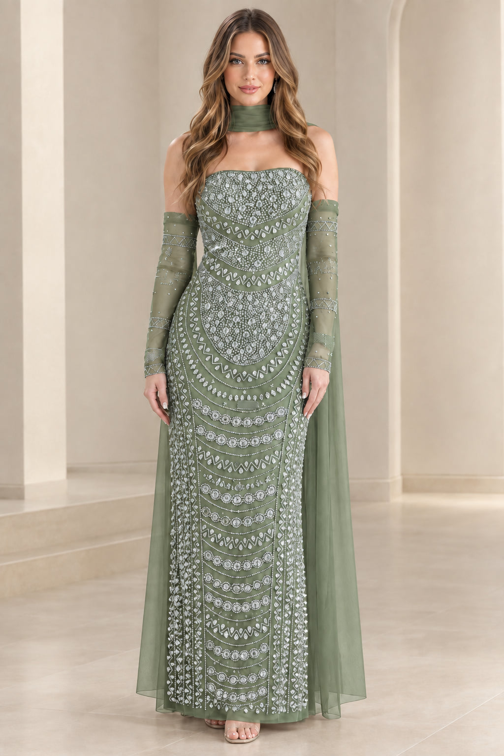 Model wearing sage green beaded strapless evening gown with flowing cape sleeves
