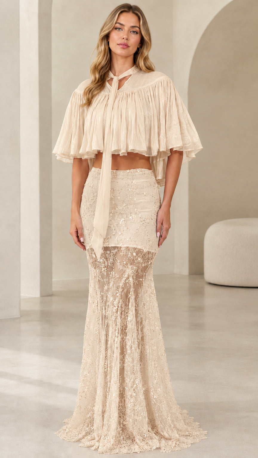 Model wearing champagne beige sequin lace two-piece formal dress with capelet overlay